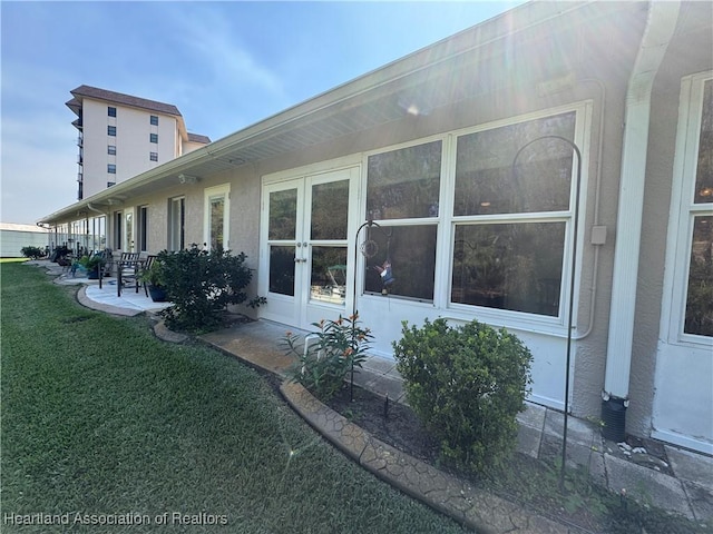 view of side of home featuring a yard, a patio, and stucco siding