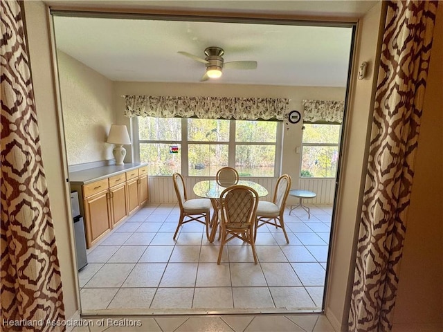 dining area with light tile patterned floors, a ceiling fan, and a textured wall