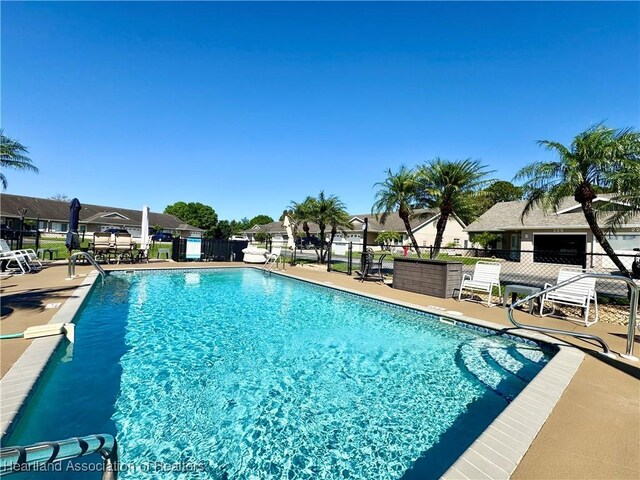 community pool with a patio area, a residential view, and fence