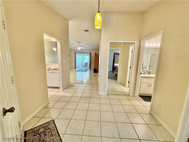 corridor featuring light tile patterned floors, baseboards, and a sink