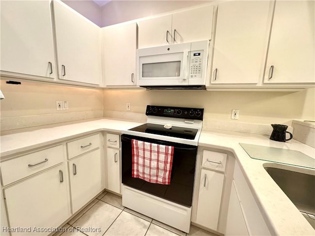 kitchen featuring range with electric cooktop, white microwave, white cabinets, and light countertops