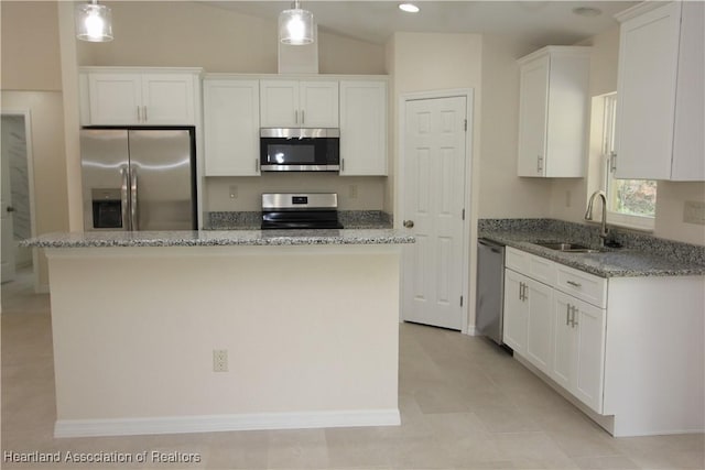 kitchen with stainless steel appliances, sink, decorative light fixtures, a center island, and white cabinetry