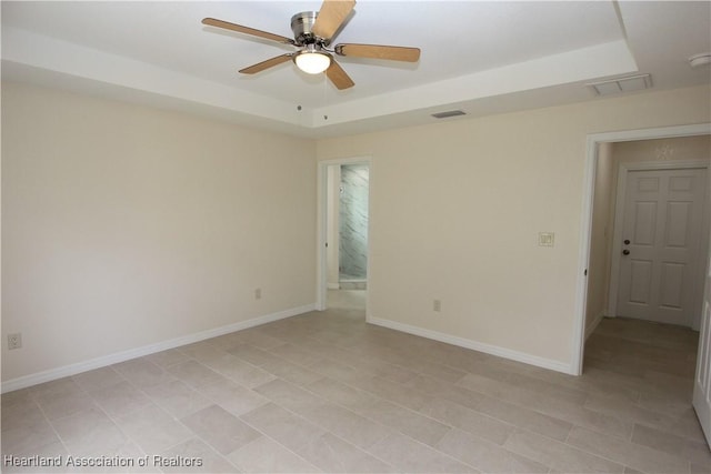 unfurnished room featuring a raised ceiling and ceiling fan