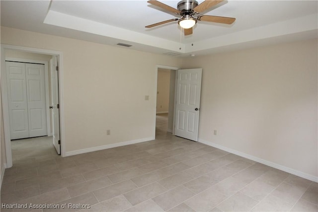 spare room featuring a tray ceiling and ceiling fan