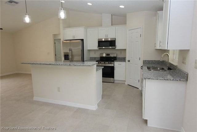 kitchen with appliances with stainless steel finishes, sink, white cabinets, a kitchen island, and hanging light fixtures