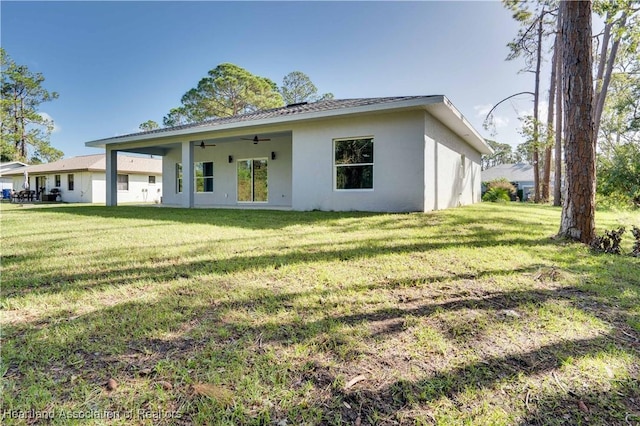 rear view of house with ceiling fan and a yard