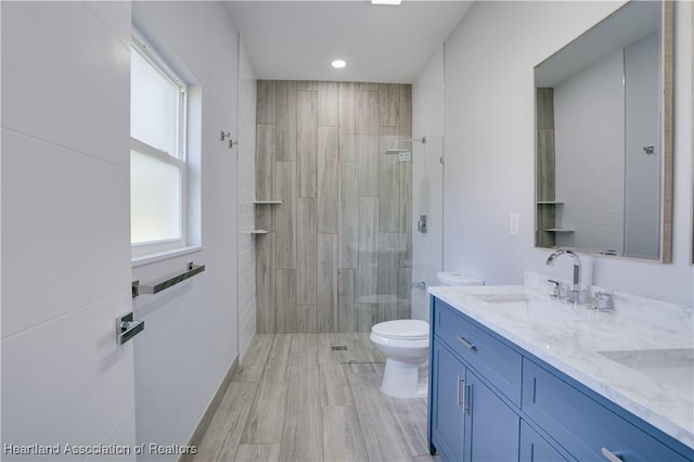 bathroom with a tile shower, vanity, hardwood / wood-style flooring, and toilet