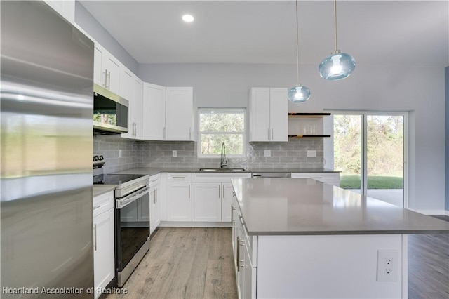 kitchen featuring a center island, white cabinets, sink, appliances with stainless steel finishes, and decorative light fixtures