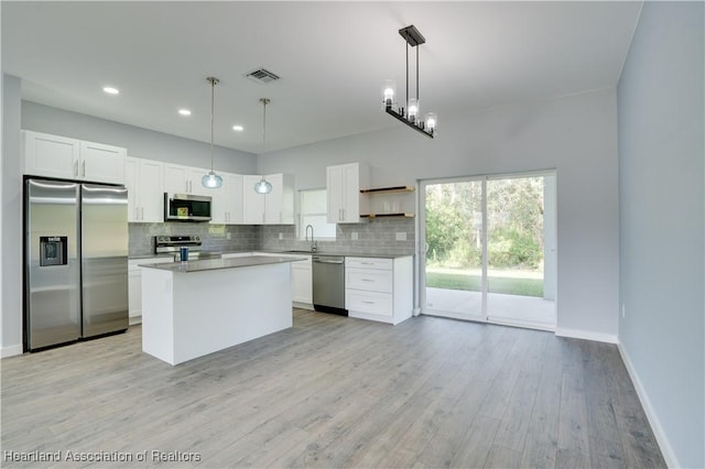 kitchen with pendant lighting, stainless steel appliances, white cabinetry, and sink