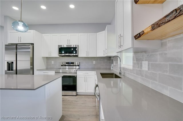 kitchen with sink, stainless steel appliances, backsplash, decorative light fixtures, and white cabinets