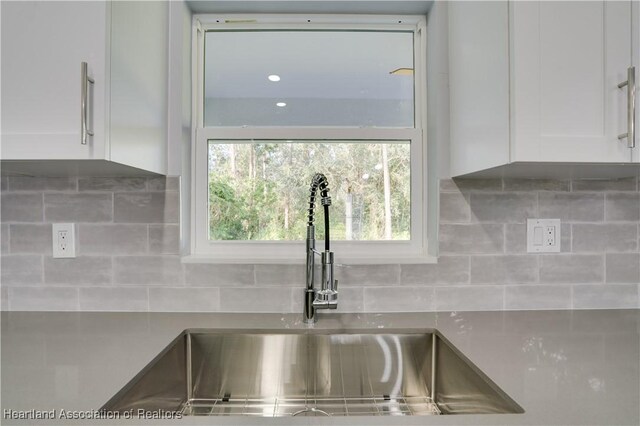 details featuring tasteful backsplash, sink, and white cabinets