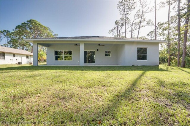 back of house with a lawn and ceiling fan