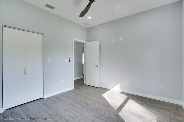 unfurnished bedroom with ceiling fan, a closet, and light hardwood / wood-style flooring