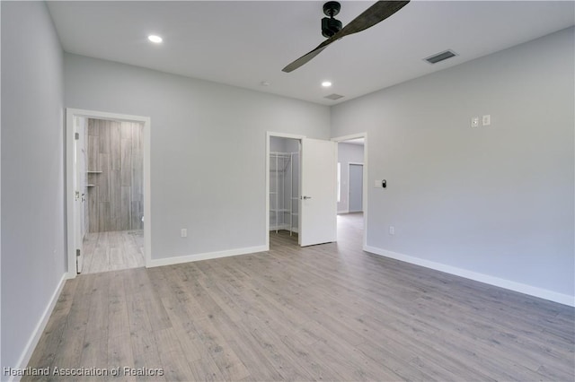 unfurnished bedroom with light hardwood / wood-style flooring, ceiling fan, a spacious closet, connected bathroom, and a closet