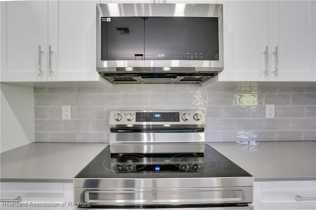 kitchen featuring white cabinets, backsplash, and appliances with stainless steel finishes