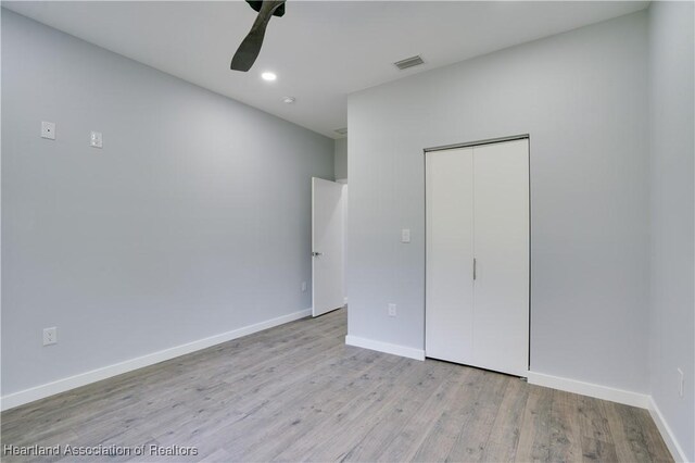 unfurnished bedroom with ceiling fan, light wood-type flooring, and a closet