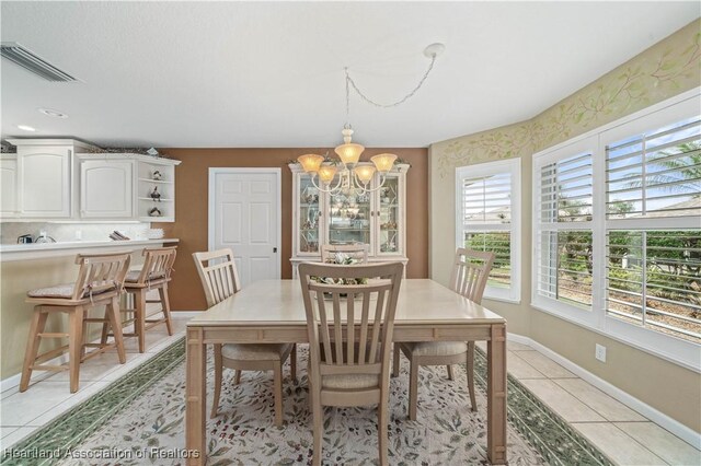 dining space with light tile patterned flooring and an inviting chandelier