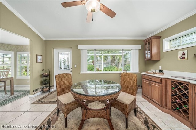 tiled dining area with ornamental molding, plenty of natural light, lofted ceiling, and ceiling fan