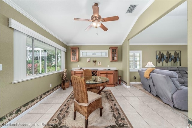 tiled dining room featuring ceiling fan, crown molding, and vaulted ceiling