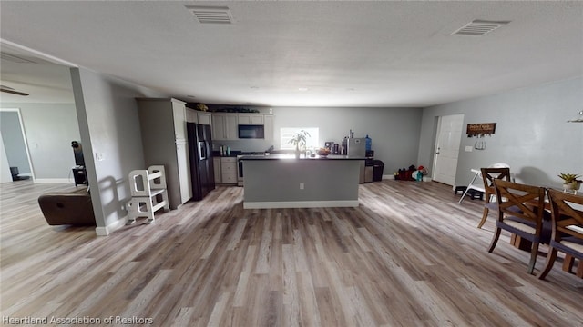 kitchen with black appliances, white cabinets, light hardwood / wood-style flooring, and a textured ceiling