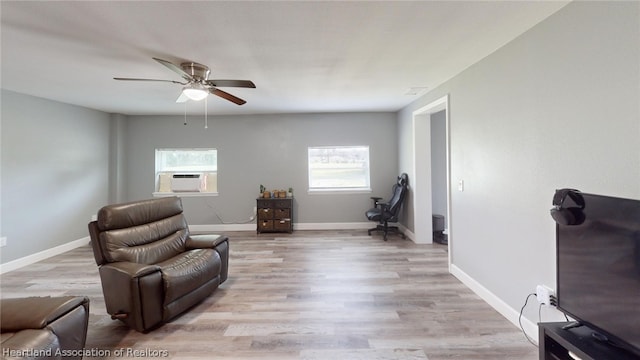 living area with ceiling fan, cooling unit, light wood-type flooring, and a healthy amount of sunlight