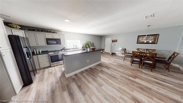 kitchen with a textured ceiling, white cabinets, sink, light hardwood / wood-style flooring, and stainless steel appliances