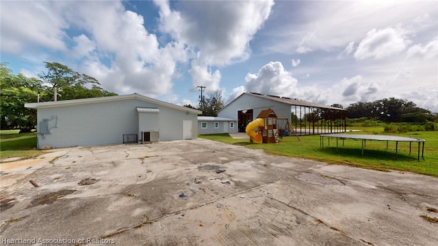 view of home's exterior featuring a yard, a playground, and a trampoline