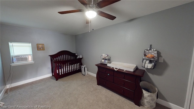 bedroom with ceiling fan, a nursery area, and light carpet