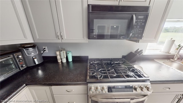 kitchen with sink, white cabinetry, and high end stove