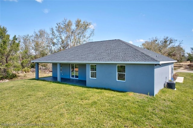 back of property featuring a shingled roof, cooling unit, a lawn, and stucco siding