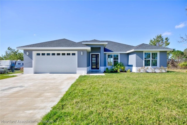 view of front of house featuring a garage, concrete driveway, a front lawn, and stucco siding