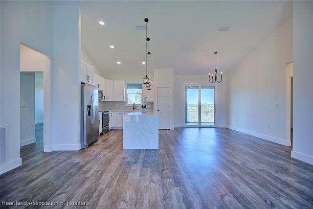 kitchen featuring a kitchen island, appliances with stainless steel finishes, open floor plan, light countertops, and white cabinetry