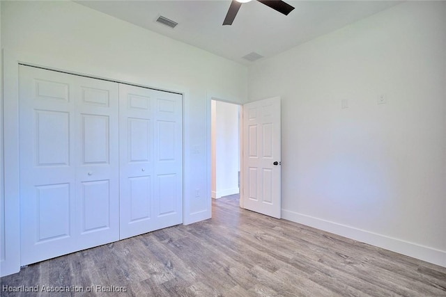 unfurnished bedroom with baseboards, visible vents, a ceiling fan, wood finished floors, and a closet