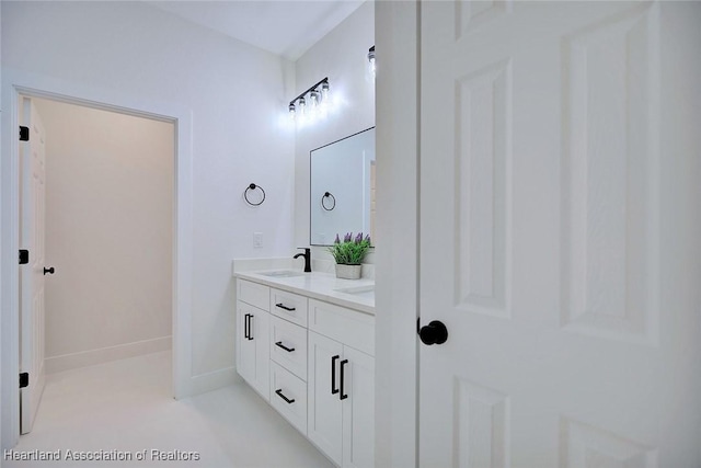 full bath with double vanity, baseboards, and a sink