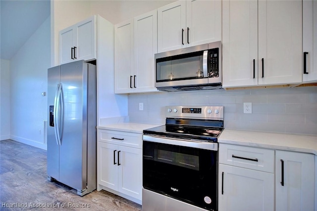 kitchen with light wood finished floors, tasteful backsplash, baseboards, stainless steel appliances, and white cabinetry