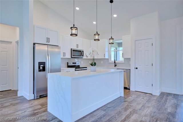 kitchen with a kitchen island, appliances with stainless steel finishes, light countertops, white cabinetry, and a sink