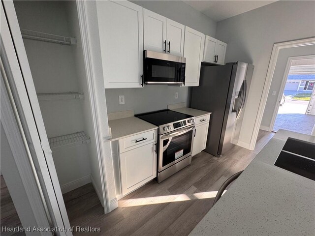 1940 Alan St, Sebring, FL 33875 - kitchen with hardwood / wood-style floors, white cabinetry, and appliances with stainless steel finishes