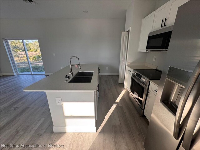 1940 Alan St, Sebring, FL 33875 - kitchen with appliances with stainless steel finishes, dark hardwood / wood-style flooring, sink, a center island with sink, and white cabinets