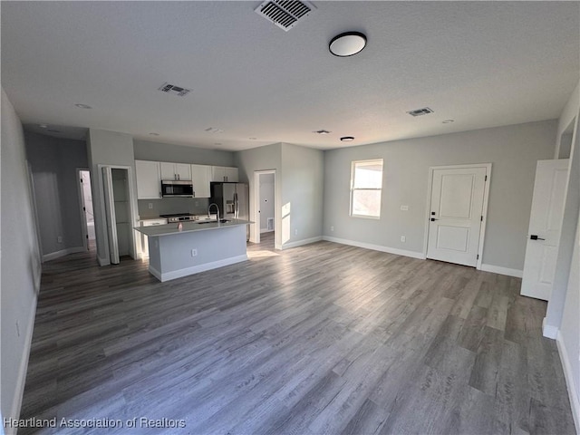 kitchen featuring sink, hardwood / wood-style flooring, an island with sink, white cabinetry, and stainless steel appliances