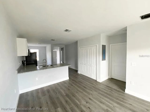 kitchen with kitchen peninsula, white cabinetry, fridge, and sink