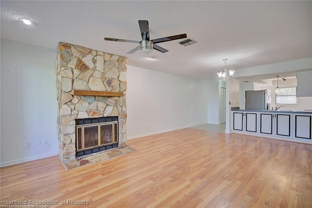 4524 Lafayette Ave, Sebring, FL 33875 - unfurnished living room featuring light wood finished floors, a textured ceiling, a stone fireplace, a ceiling fan, and baseboards