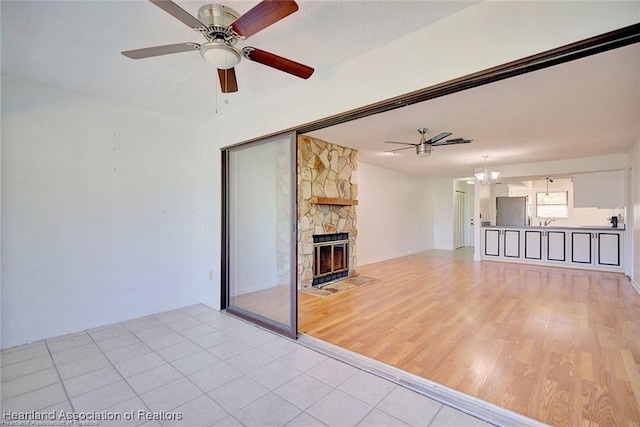 4524 Lafayette Ave, Sebring, FL 33875 - unfurnished living room featuring ceiling fan, a chandelier, a fireplace, and light tile patterned floors