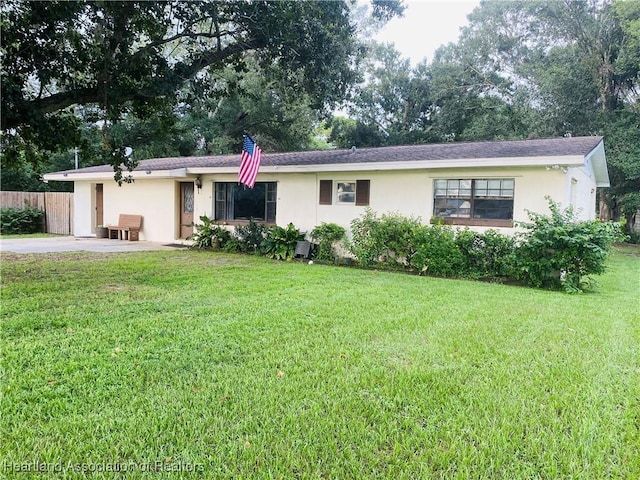 ranch-style house with a front yard, stucco siding, and fence