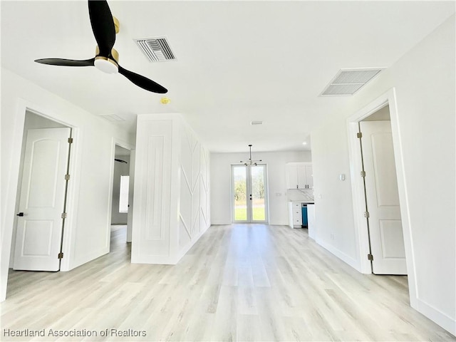 unfurnished living room featuring light wood-type flooring and ceiling fan with notable chandelier