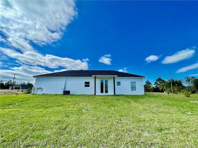 back of property with central air condition unit and a yard