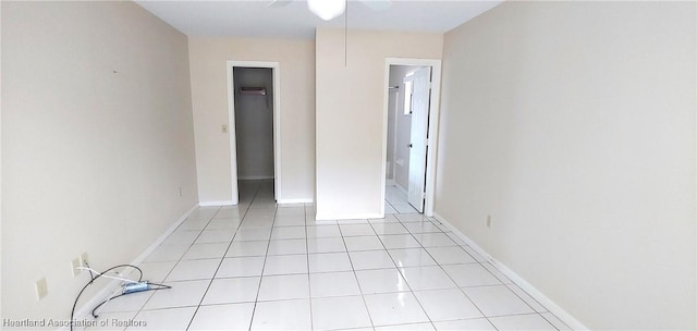 unfurnished bedroom featuring light tile patterned floors, a walk in closet, and baseboards