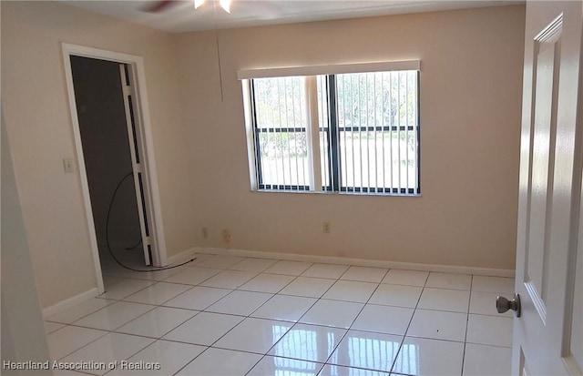 spare room with light tile patterned floors, a ceiling fan, and baseboards