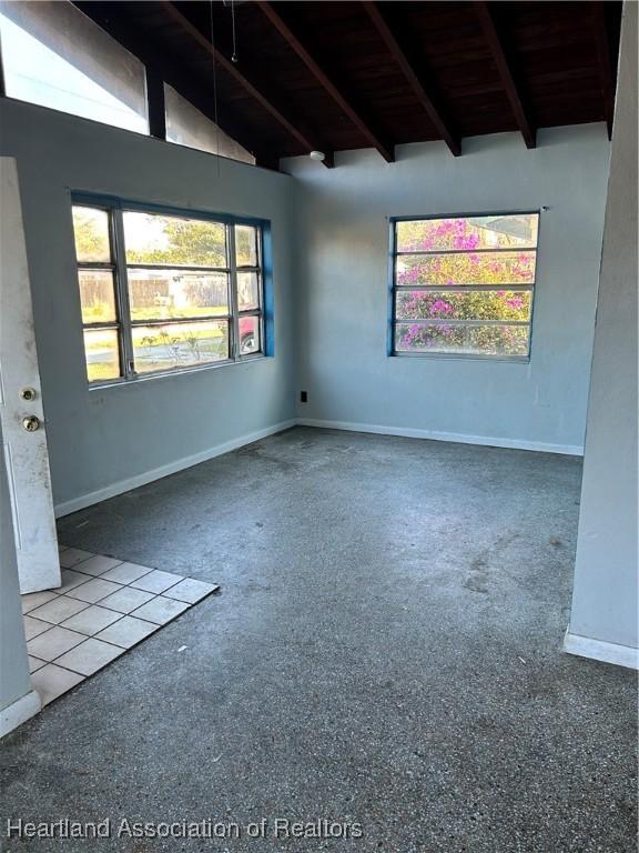 carpeted spare room featuring beam ceiling and high vaulted ceiling