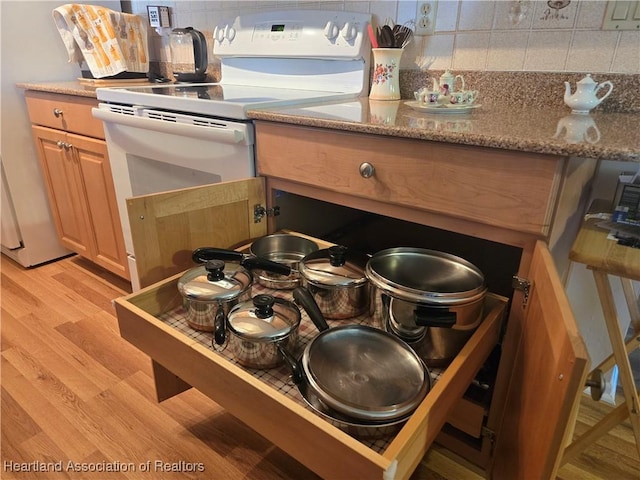 kitchen featuring light wood-style flooring, electric range, and decorative backsplash