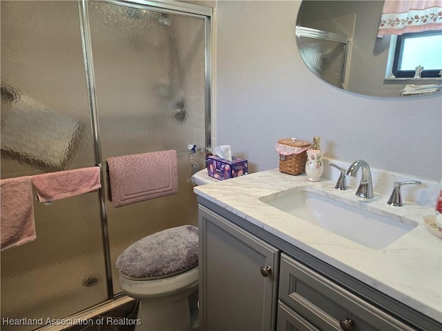 bathroom with toilet, a shower stall, and vanity